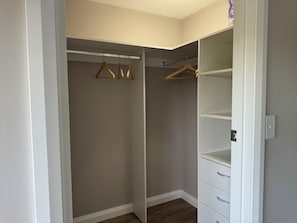 Ein begehbarer Kleiderschrank mit Kleiderstange und offenen Regalen.