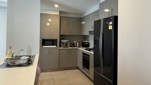 Eine moderne Küche mit Edelstahlgeräten, einer Mikrowelle, einer Kaffeemaschine und einem Kühlschrank.