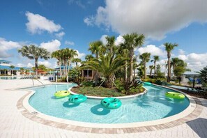A swimming pool with multiple lanes, surrounded by palm trees and a clear sky. - 5BR resort townhome with private pool, game room & Windsor Island access. (Davenport)
