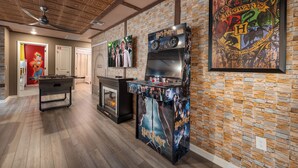 A room with a foosball table, a fireplace, and a wall decorated with Harry Potter-themed artwork. - Premium 5-Bedroom Resort Pool Home (Davenport)