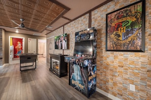 A room with a foosball table, a fireplace, and a wall decorated with Harry Potter-themed artwork. - Premium 5-Bedroom Resort Pool Home (Davenport)
