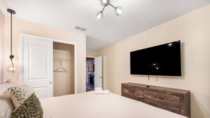 A bedroom with a bed, a dresser, a TV, and a closet. - Premium 5-Bedroom Resort Pool Home (Davenport)