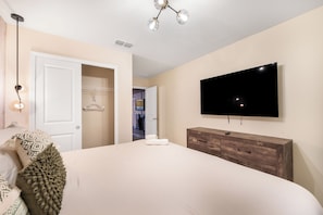 A bedroom with a bed, a dresser, a TV, and a closet. - Premium 5-Bedroom Resort Pool Home (Davenport)