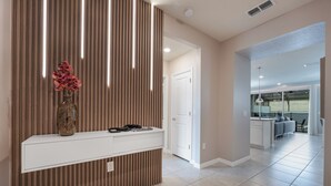 A modern interior with a wooden accent wall, a white console table, and a door leading to a balcony. - Premium 5-Bedroom Resort Pool Home (Davenport)