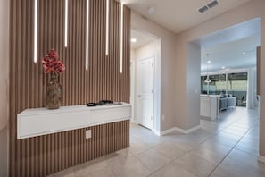 A modern interior with a wooden accent wall, a white console table, and a door leading to a balcony. - Premium 5-Bedroom Resort Pool Home (Davenport)