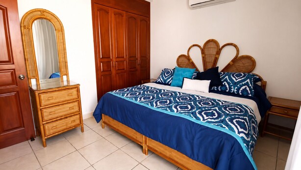 Un dormitorio con cama, armario de madera, cómoda y espejo.