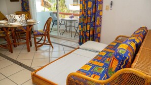 Una habitación con sofá, una mesa de comedor con sillas y un balcón con mesa y sillas.