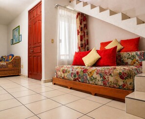 Ein Schlafzimmer mit einem Bett, einer hölzernen Bank, einer roten Tür und einer Treppe.