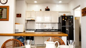 A modern kitchen with white cabinets, a black refrigerator, and a wooden countertop. - Dept. Exclusive Ixtapa (Ixtapa Zihuatanejo)