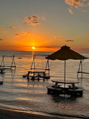 A beach scene with a sunset, wooden picnic tables, and a canopy structure. - Secret Beach Escape with Pool! Off Season Rates! (San Pedro)