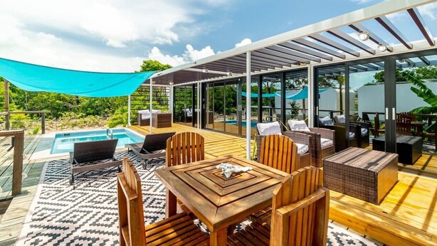 A covered outdoor area with a pool, wooden furniture, and a glass enclosure. - Secret Beach Escape with Pool! Off Season Rates! (San Pedro)