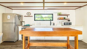 A modern kitchen with a large wooden table, stainless steel appliances, and a window with a view of greenery. - Secret Beach Escape with Pool! Off Season Rates! (San Pedro)
