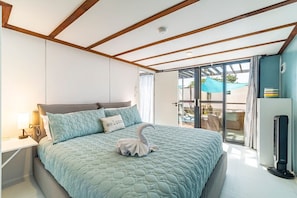 Ein Schlafzimmer mit einem Bett, einem Nachttisch, einem Fenster und Blick ins Freie.