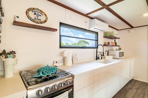 A kitchen with a gas stove, a microwave, and a window above the sink. - Secret Beach Escape with Pool! Off Season Rates! (San Pedro)