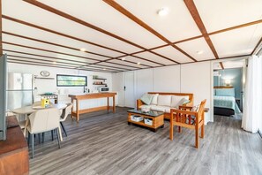 Ein kompakter Wohnbereich mit Küchenzeile, Essplatz, Sofa und Bett.