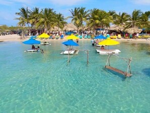 A clear blue water body with a beach and palm trees in the background. - Secret Beach Escape with Pool! Off Season Rates! (San Pedro)