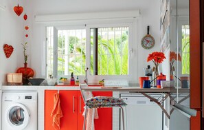 A kitchen with a washing machine, a dining area with a table and chairs, and large windows with a view of greenery. - Gorgeous home in Mojacar with private swimming pool, can be inside or outside (Mojacar)