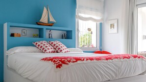 Ein Schlafzimmer mit einem Bett, einer Segelboot-Dekoration, einem Fenster mit Vorhängen und einer Regalwand.
