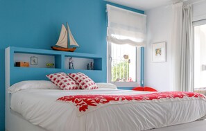 A bedroom with a bed, a sailboat decoration, a window with curtains, and a wall with shelves. - Gorgeous home in Mojacar with private swimming pool, can be inside or outside (Mojacar)