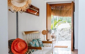 A room with a white sofa, a red hat, a woven wall hanging, and a view of greenery outside. - Gorgeous home in Mojacar with private swimming pool, can be inside or outside (Mojacar)