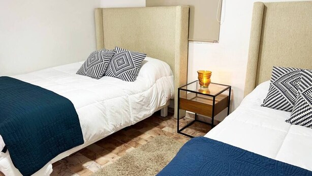 A hotel room with two beds, a nightstand with a lamp, and a carpeted floor. - TOP/3BR/First Line Ocean Front Villa/2 Terrace/HZ (Cancún)