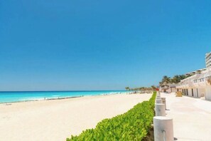 Ein Hotel direkt am Strand mit freiem Blick auf den Ozean, einem Sandstrand und einer Reihe von Gebäuden im einheitlichen Baustil.