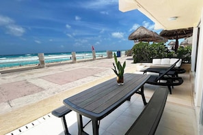 A terrace with a view of the beach and ocean, outdoor seating, and a thatched umbrella. - Top · Villa frente al mar · Playa a unos pasos (Cancún)