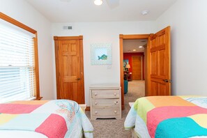 A bedroom with two beds, a dresser, and a hallway leading to another room. - Oceanside, 2 Hot Tubs- 2 Duplex's rents as 1-BU22, Love R Shack at the Beach (Corolla)