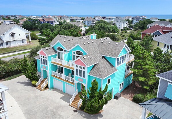 A large, multi-story house with a prominent front porch and a garage. - Oceanside, 2 Hot Tubs- 2 Duplex's rents as 1-BU22, Love R Shack at the Beach (Corolla)
