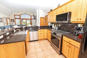 A modern kitchen with wooden cabinets, a stainless steel refrigerator, a built-in microwave, and a gas stove. - Oceanside, 2 Hot Tubs- 2 Duplex's rents as 1-BU22, Love R Shack at the Beach (Corolla)