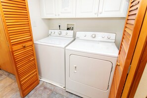 A laundry room with two white washers and dryers, wooden slatted doors, and a tiled floor. - Oceanside, 2 Hot Tubs- 2 Duplex's rents as 1-BU22, Love R Shack at the Beach (Corolla)