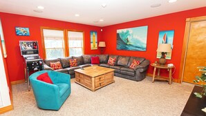 A living room with a sectional sofa, a blue armchair, a wooden coffee table, and a television. - Oceanside, 2 Hot Tubs- 2 Duplex's rents as 1-BU22, Love R Shack at the Beach (Corolla)