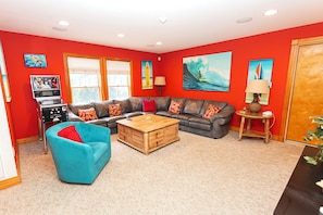 Ein Wohnzimmer mit einem Ecksofa, einem blauen Sessel, einem Holztisch und einem Fernseher.
