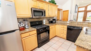A modern kitchen with stainless steel appliances, wooden cabinets, and a granite countertop. - Oceanside, 2 Hot Tubs- 2 Duplex's rents as 1-BU22, Love R Shack at the Beach (Corolla)