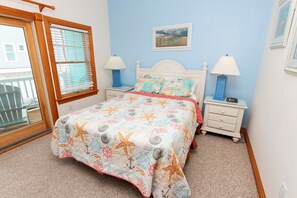 A bedroom with a bed, two nightstands, a window with blinds, and a picture on the wall. - Oceanside, 2 Hot Tubs- 2 Duplex's rents as 1-BU22, Love R Shack at the Beach (Corolla)