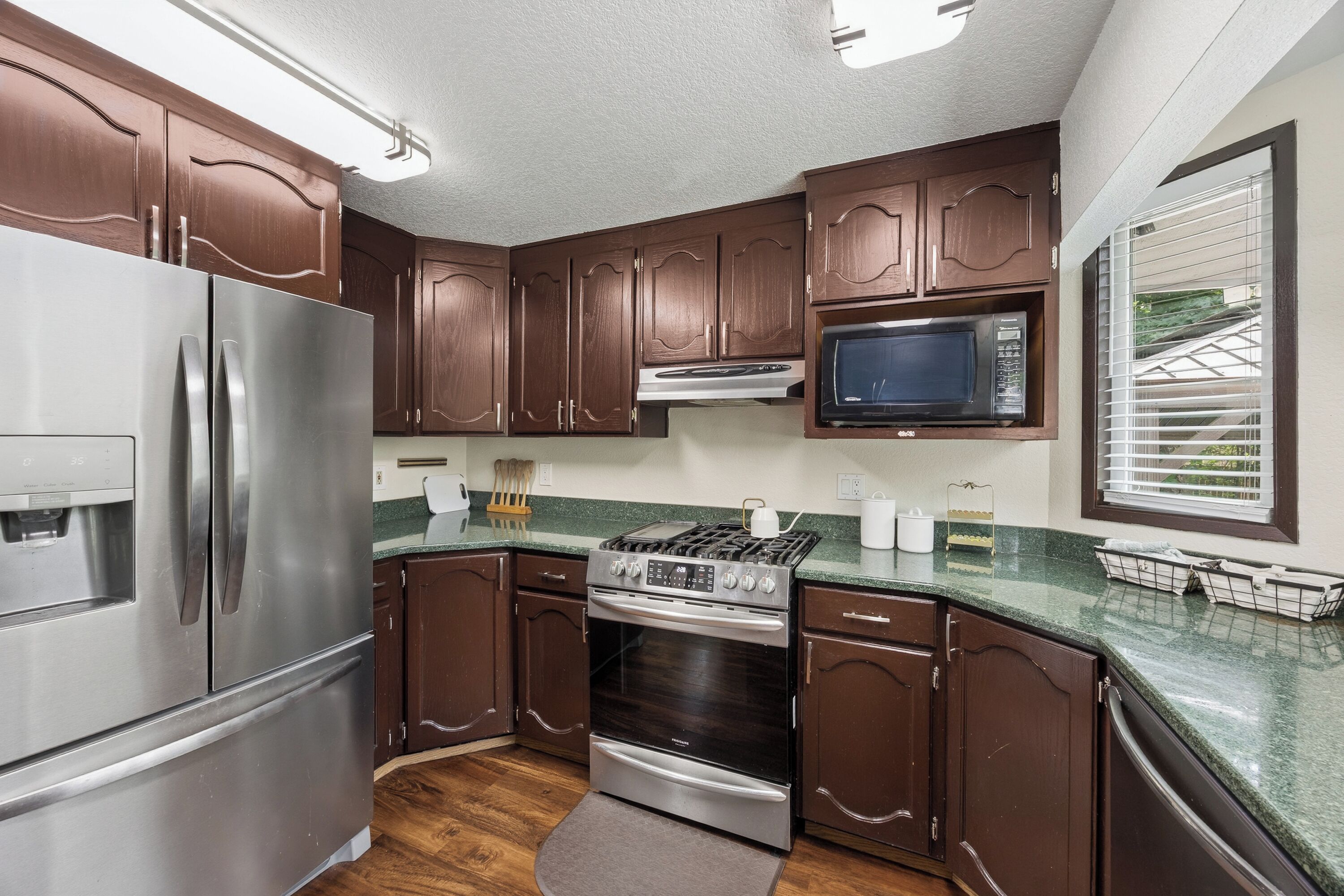 A compact kitchen with a refrigerator, stove, microwave, and wooden cabinets.