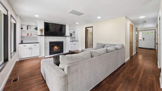 Un salón moderno con chimenea, un televisor de pantalla plana grande y un sofá gris.