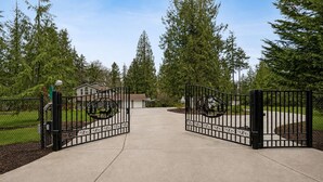 Un camino de entrada con puerta cerrada que conduce a una propiedad residencial con una casa al fondo.