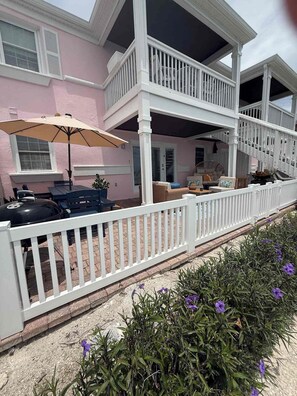 A pink house with a covered porch, outdoor furniture, and a barbecue grill. - St. Pete Coastal Retreat with beautiful water view (St. Petersburg)