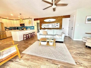 A modern living room with a sofa, coffee table, and a kitchen area in the background. - St. Pete Coastal Retreat with beautiful water view (St. Petersburg)