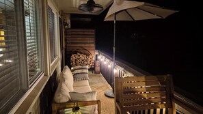 Ein Balkon mit einer Couch, einem Stuhl, einem Tisch und einem großen Sonnenschirm.