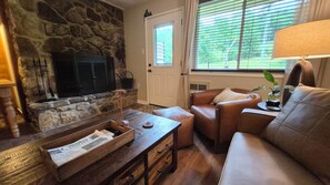 A cozy living room with a stone fireplace, leather furniture, and a window with blinds. - Newly Renovated Slopeside Condo at Bryce Resort. Family and pet-friendly! (Mount Jackson)