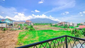 Un quartier résidentiel avec des maisons et un terrain verdoyant, vu depuis un balcon doté d’une rambarde en métal.
