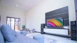 Un salon avec un canapé gris, un téléviseur à écran plat et un système audio.