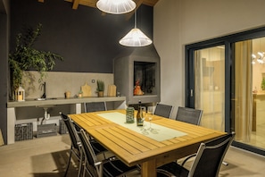 A dining area with a wooden table, chairs, pendant lights, and a fireplace. - Villa Lenko (Istria - Svetvinčenat) (Svetvinčenat)