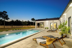 Une piscine avec des chaises longues et un espace patio.