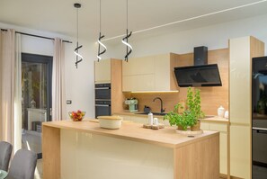 Eine moderne Küche mit einer zentralen Kochinsel, einem eingebauten Backofen und einer Mikrowelle.