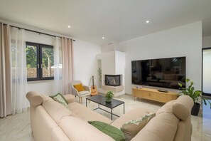Un salon moderne avec un canapé, une table basse, un téléviseur et une guitare.