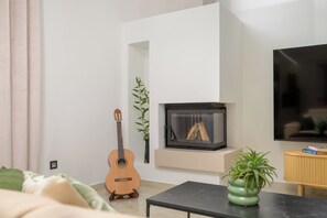 En moderne stue med pejs, fjernsyn og guitar.