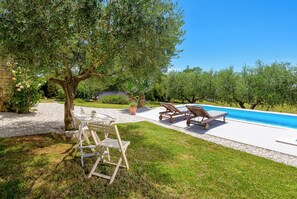 Ein Poolbereich mit Baum, zwei Liegestühlen und einem Tisch.